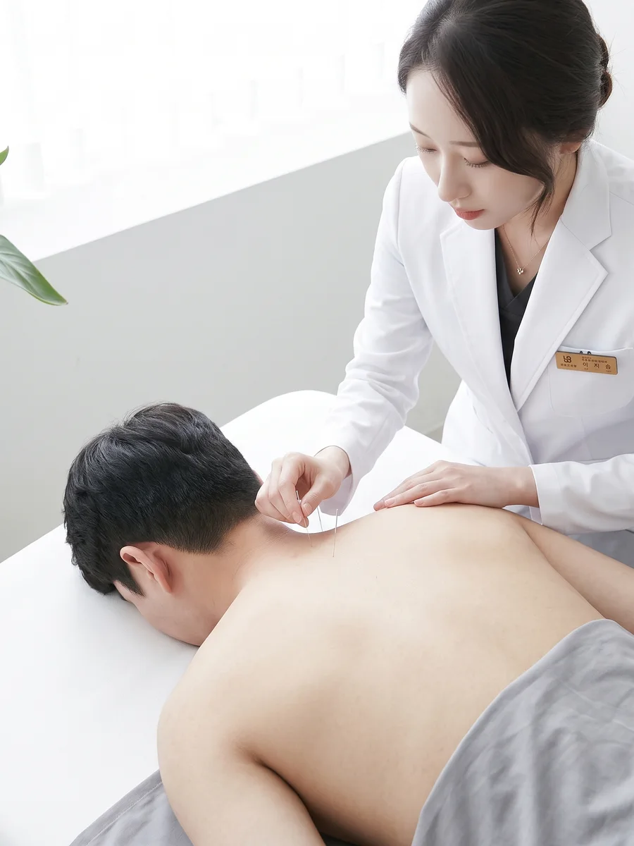한의사가 환자의 등과 목 부위에 침 치료를 하는 모습